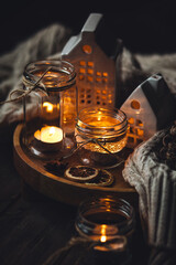 Cozy home holiday atmosphere. Idea for handmade christmas decorations: aromatic candles in glass jars. Cinnamon sticks, anise, dry citrus, homemade gingerbread cookies. Fairy lights
