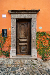 Front view of colonial house door with stone frame and climbing vine in historic center of San Miguel de Allende, Mexico