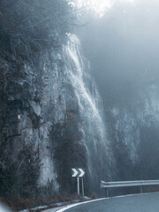 Waterfall by the road in foggy mountain