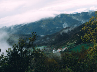 Misty valley with green fields and village