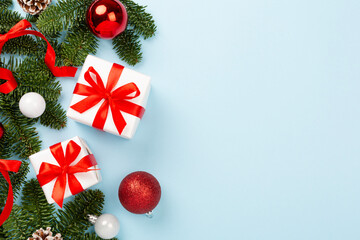 Festive Christmas tree branches with gift box on color background, top view