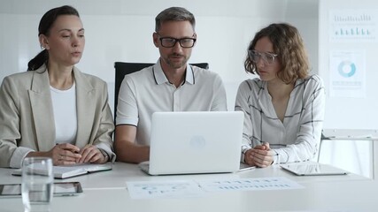 Professional team analyzing data on laptop, sharing insights during collaborative office meeting, highlighting workplace synergy and strategic planning