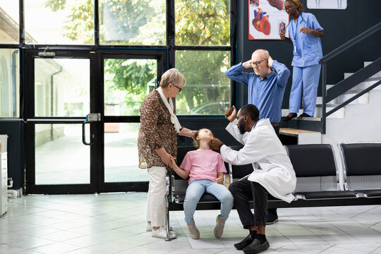 Grandparents in panic after granddaughter fainted in clinic lobby, urgently seeking help from black doctor during medical emergency. Hospital staff respond to unconscious child in crisis. - Powered by Adobe