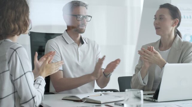 Professional team applauding, celebrating collaborative success and recognizing outstanding performance during corporate meeting, expressing shared workplace achievement