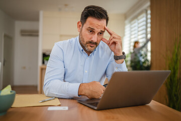 Businessman feeling stressed while working from home office