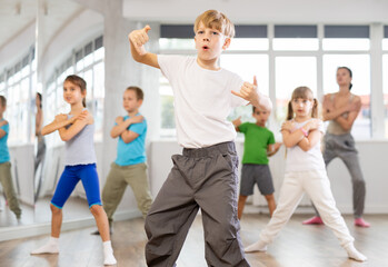 Fototapeta premium Group of preteen girls and boys enjoying active dance movement in modern studio