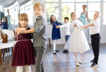 Smiling little boys and girls dancing pair dance in the ballet studio