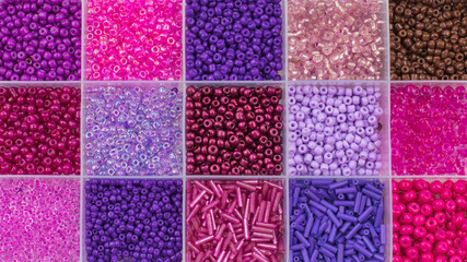 Close up of colorful seed beads in square sections purple and pink shades, flat lay