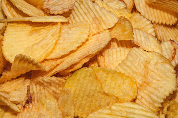 Crispy golden potato chips in a close-up shot. Crunchy salted snack with ridged texture. Perfect for casual eating, parties and fast food cravings. Classic savory junk food favorite.