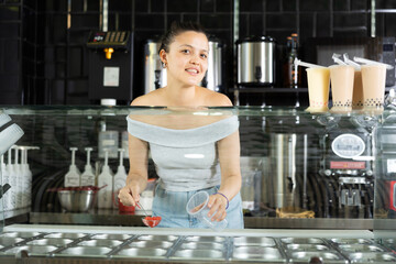 Young woman putting juice balls for bubble tea in plastic cup