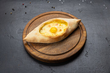 Traditional Georgian Adjarian khachapuri with eggs and cheese on a wooden board