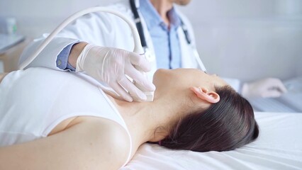 Obraz premium Doctor man is using ultrasound equipment on neck of female patient lying down for a medical examination. Medicine and science