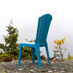 Vibrant blue chair on rocky terrain overlooking misty landscape