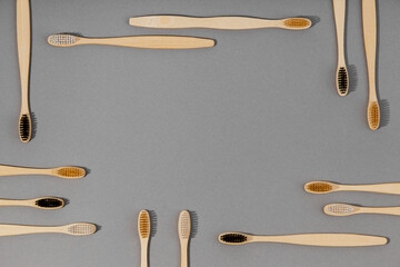 Several wooden bamboo toothbrushes arranged in the shape of a frame on grey background. Eco-friendly oral hygiene products. Taken from a top view and flat lay.