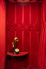 Plush red velvet walls frame a golden candlestick telephone in this vintage-inspired booth—ideal for editorial, cinematic themes, or historic design collections.