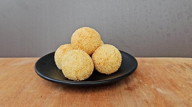 cookies in a bowl,Sesame balls or Onde onde or Jiandui or Kue moci or Kuih bom,a type of Chinese pastry,made from glutinous rice,coated with sesame seeds,filled with a filling usually beans,served wit