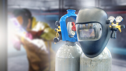 Fototapeta premium Welding mask and gas cylinders with gauges in workshop, welder working in background, metal fabrication, industrial welding, manufacturing, engineering.