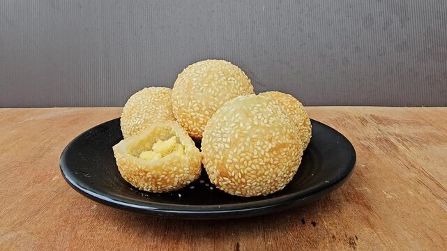cookies on a plate,Sesame balls or Onde onde or Jiandui or Kue moci or Kuih bom,a type of Chinese pastry,made from glutinous rice,coated with sesame seeds,filled with a filling usually beans,served wi