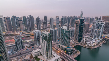 Obraz premium Aerial top view of Dubai Marina night to day timelapse. Modern towers and traffic on the road