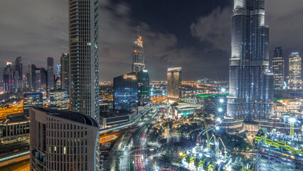 Fototapeta premium Panoramic skyline view of Dubai downtown with mall, fountains and skyscrapers aerial night timelapse