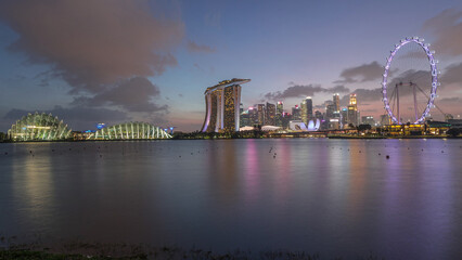 Obraz premium Downtown skyline of Singapore as viewed from across the water from The Garden East day to night timelapse. Singapore.