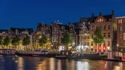 Panoramic timelapse hyperlapse of the illuminated famous Dancing Houses along the Amstel River day to night transition. Amsterdam, Netherlands