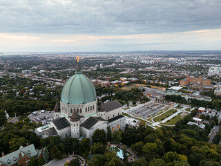 Fototapeta premium Aerial view of Saint Joseph's Oratory in Montreal at sunset, with cityscape and greenery. g.