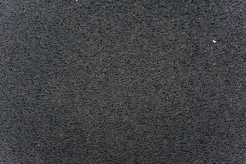 Close-up texture of black synthetic doormat material with tangled fibers, abstract dark background.