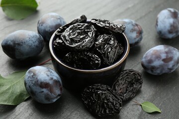 Dried prunes and fresh plums on black table, closeup