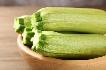 Fresh ripe zucchinis in bowl on table, closeup