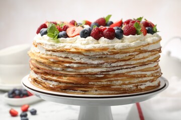 Delicious crepe cake with fresh berries on white table, closeup