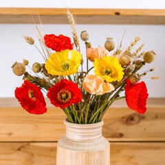 Vibrant bouquet of poppies with wheat in rustic vase