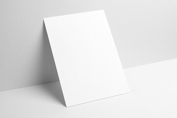 Fototapeta premium Blank white card standing upright on a textured gray surface with subtle lighting