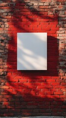 Blank white canvas hanging on a rustic red brick wall with natural shadows falling across it