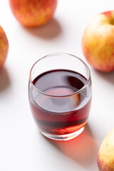 Glass of apple cider with red apple fruit on white background
