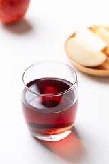 Glass of apple cider with red apple fruit on white background