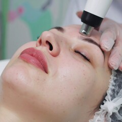 Woman receiving facial treatment with skincare device
