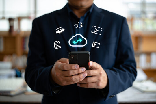 A businessman uses a smartphone to manage a cloud-based system. 
