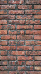A rustic red brick wall with rough texture and visible mortar. The surface shows natural weathering, cracks, and variations in color, creating an aged and vintage industrial look.