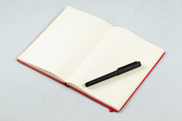 a red blanked notebook with a black pen over its right sheets