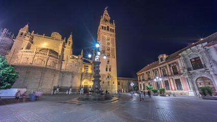 Fototapeta premium La Giralda and Seville Cathedral timelapse hyperlapse glowing under the night sky.
