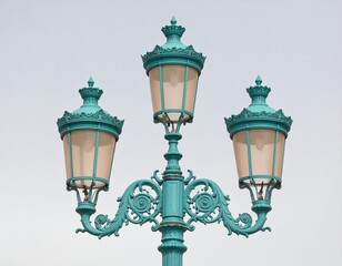Three teal-colored ornate street lamps against a pale sky