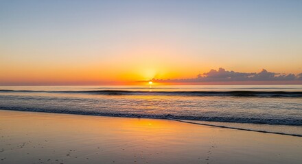 Obraz premium Serene sunrise over the ocean, painting the sky with warm orange and yellow hues.
