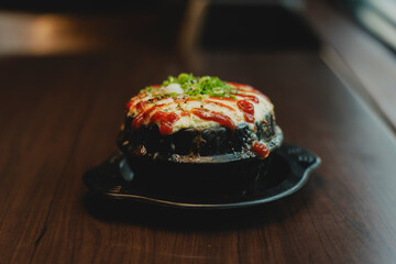 Sizzling Korean BBQ pork belly (samgyeopsal) on tabletop charcoal grill with rising smoke and traditional banchan side dishes, close-up shot in cozy restaurant setting with copy space.