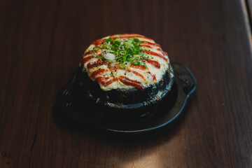 Sizzling Korean BBQ pork belly (samgyeopsal) on tabletop charcoal grill with rising smoke and traditional banchan side dishes, close-up shot in cozy restaurant setting with copy space.