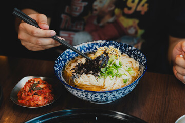 Sizzling Korean BBQ pork belly (samgyeopsal) on tabletop charcoal grill with rising smoke and traditional banchan side dishes, close-up shot in cozy restaurant setting with copy space.