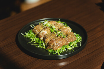Sizzling Korean BBQ pork belly (samgyeopsal) on tabletop charcoal grill with rising smoke and traditional banchan side dishes, close-up shot in cozy restaurant setting with copy space.