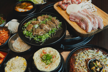 Grilled Korean beef short ribs (galbi) with caramelized edges on hot grill, served with lettuce wraps and kimchi, authentic Korean barbecue dining experience, overhead view.