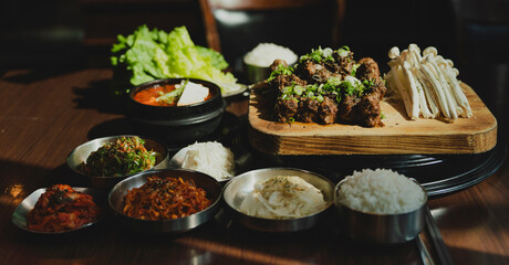 Grilled Korean beef short ribs (galbi) with caramelized edges on hot grill, served with lettuce wraps and kimchi, authentic Korean barbecue dining experience, overhead view.