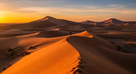 A solitary person stands with arms outstretched atop a sand dune at sunset in a vast desert landscape
